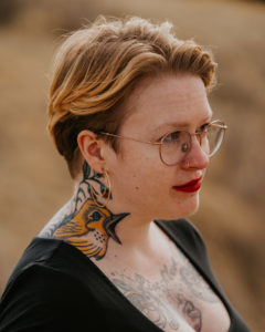 Image of a person with short strawberry blonde hair and glasses standing profile