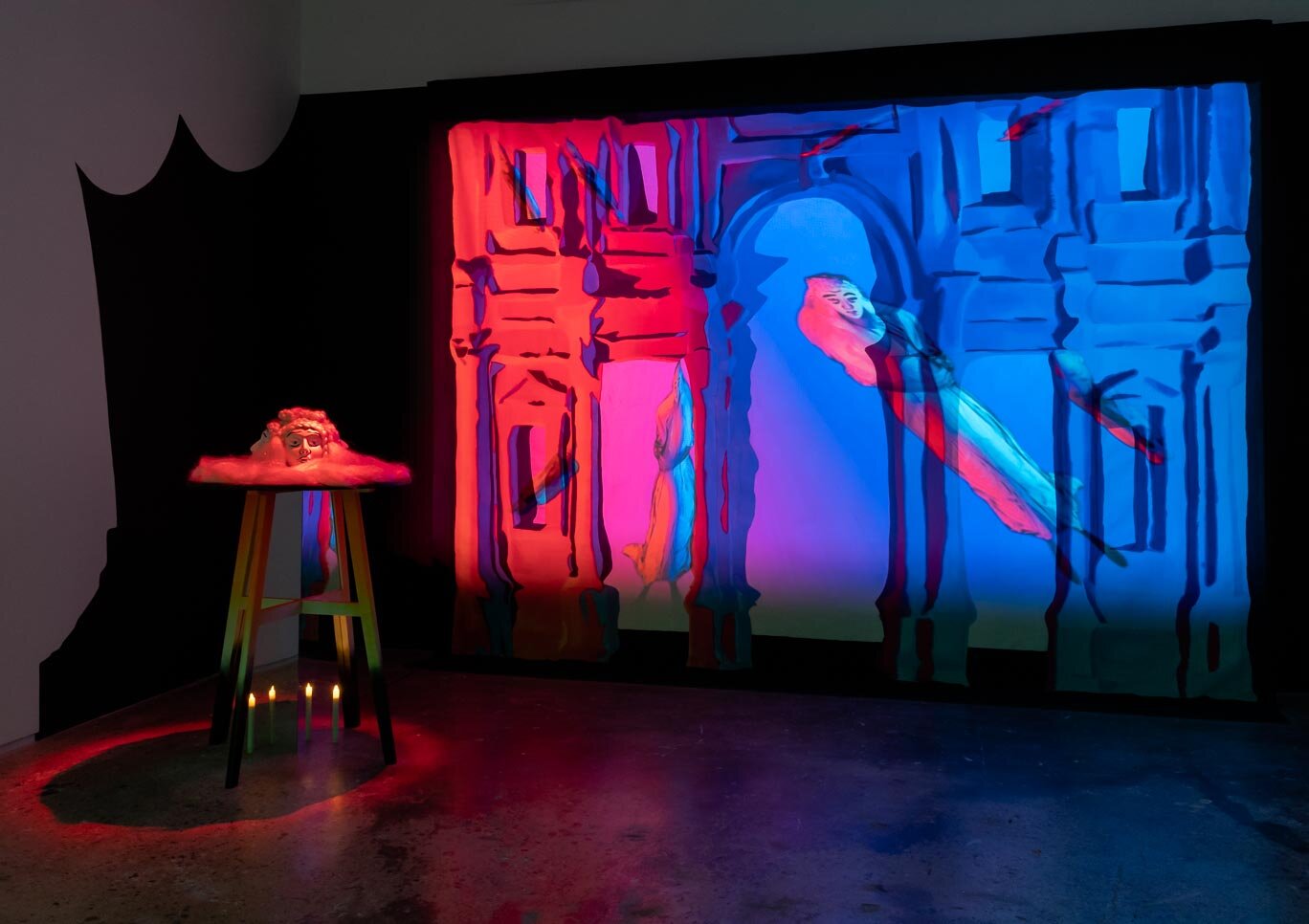 art installation with various layers, appearing like a set with a red and blue light shining on it