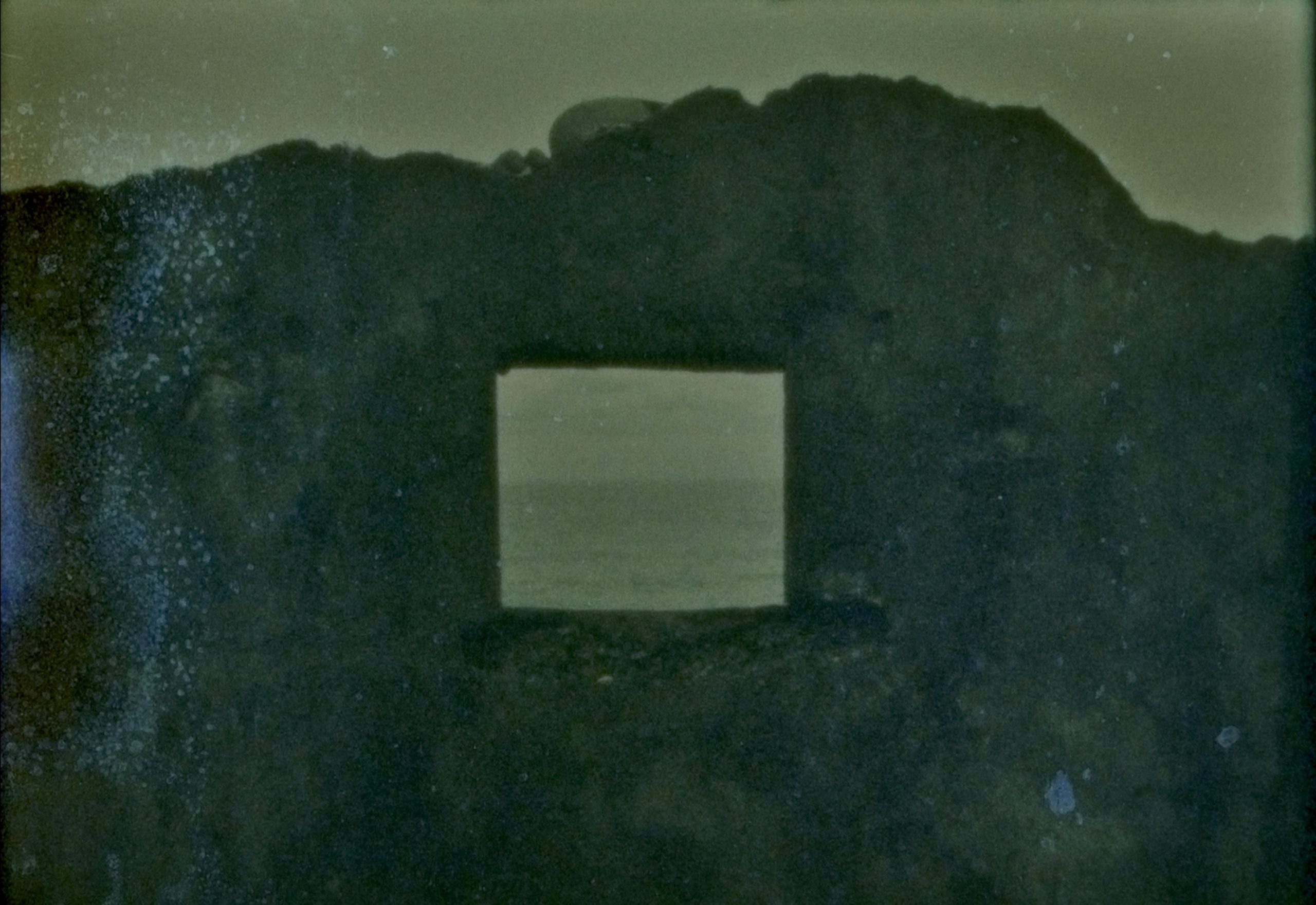 A dark rock like shape with a window hole in it