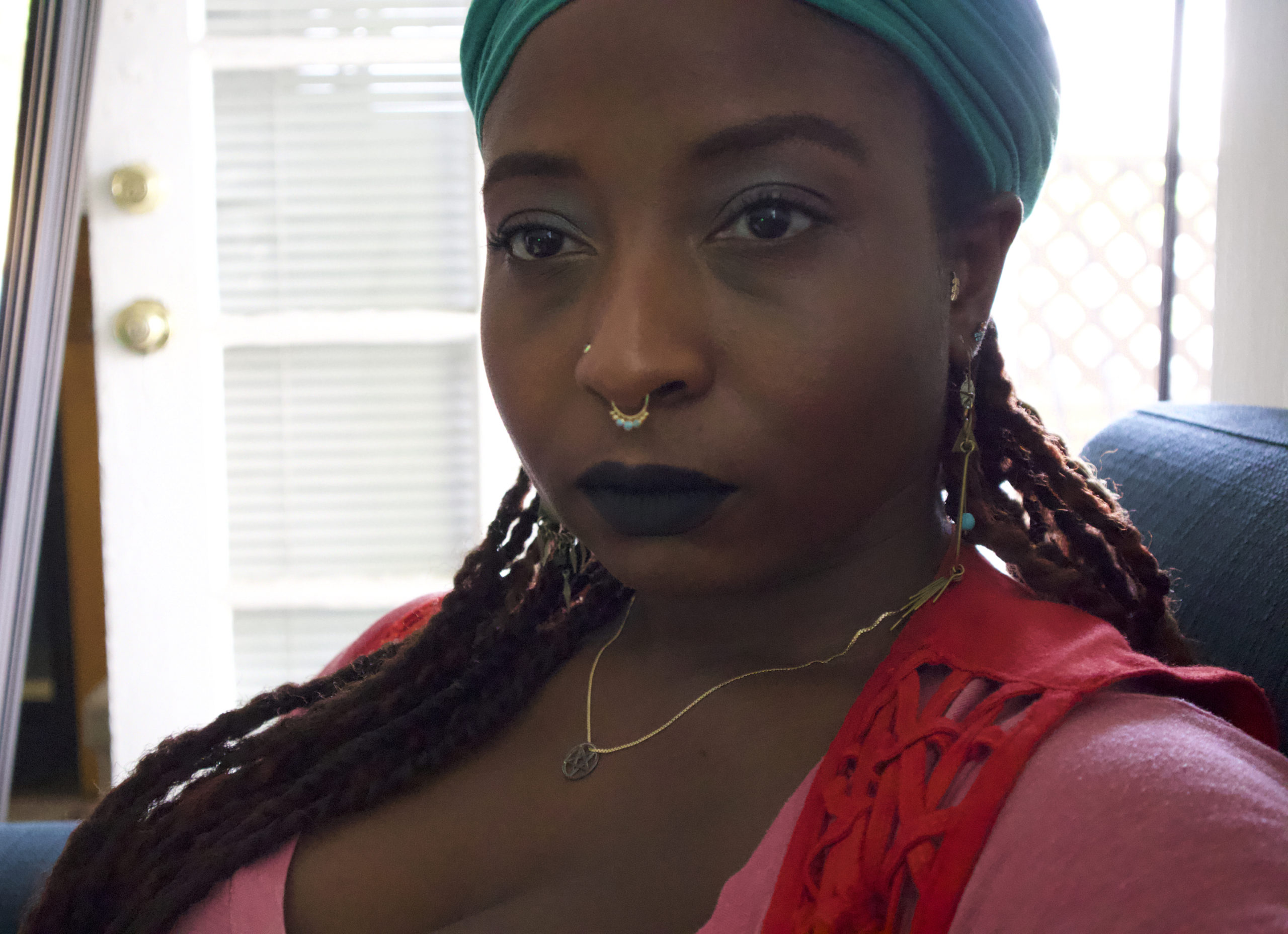 alea adigweme facing the camera weraing a red shirt and blue head scarf