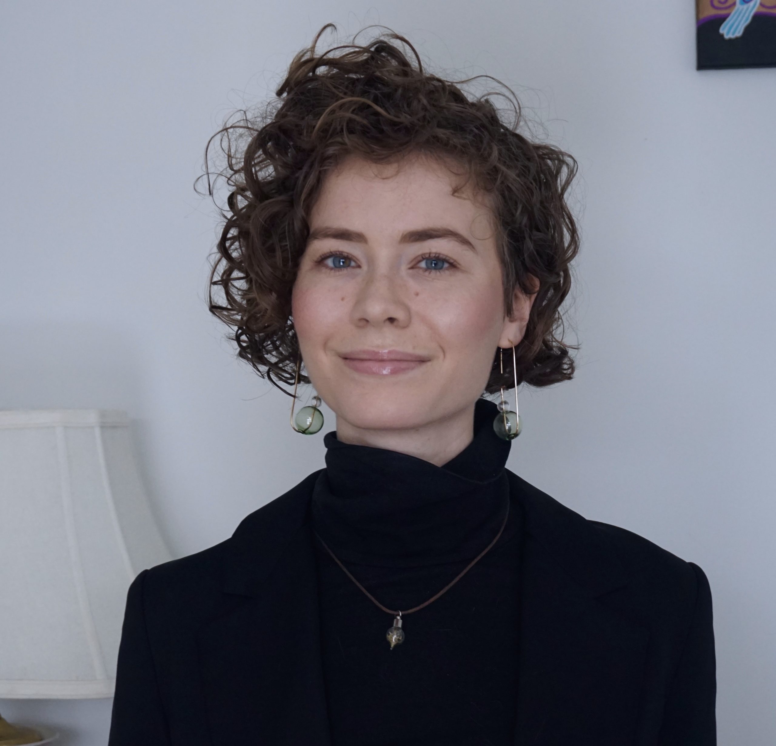 Emma Croll-Baehre smiling against a light backgroun wearing a black turtleneck