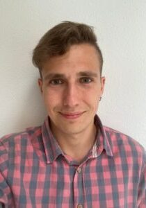 Miguel Sebastian Martin wearing a plaid shirt against a white wall