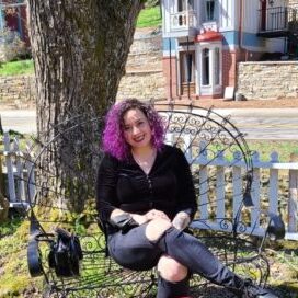 Felicia Lang seated outside on a bench under a tree on a sunny day