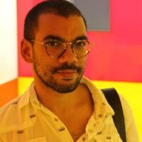 Icaro Ferraz Vidal Junior standing against a red and yellow wall wearing a yellow shirt